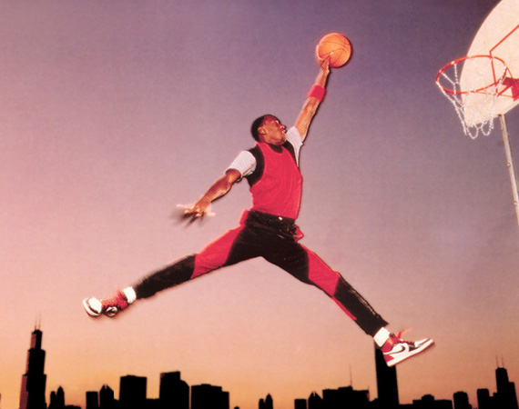MJ in a Nike jumpsuit and Jordan 1s jumping above the Chicago skyline